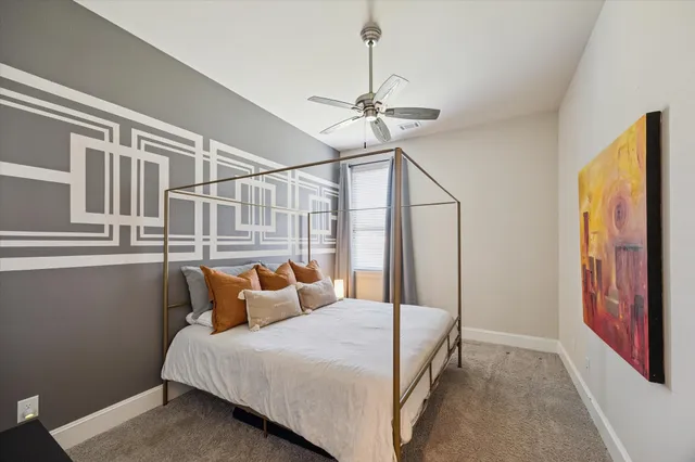 a bedroom with a bed ceiling fan and a window