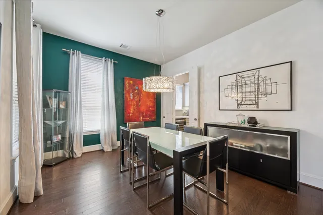 a kitchen with stainless steel appliances granite countertop a stove a refrigerator a sink a dining table and chairs with wooden floor