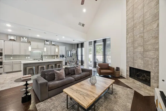 a living room with stainless steel appliances furniture a rug and a kitchen view