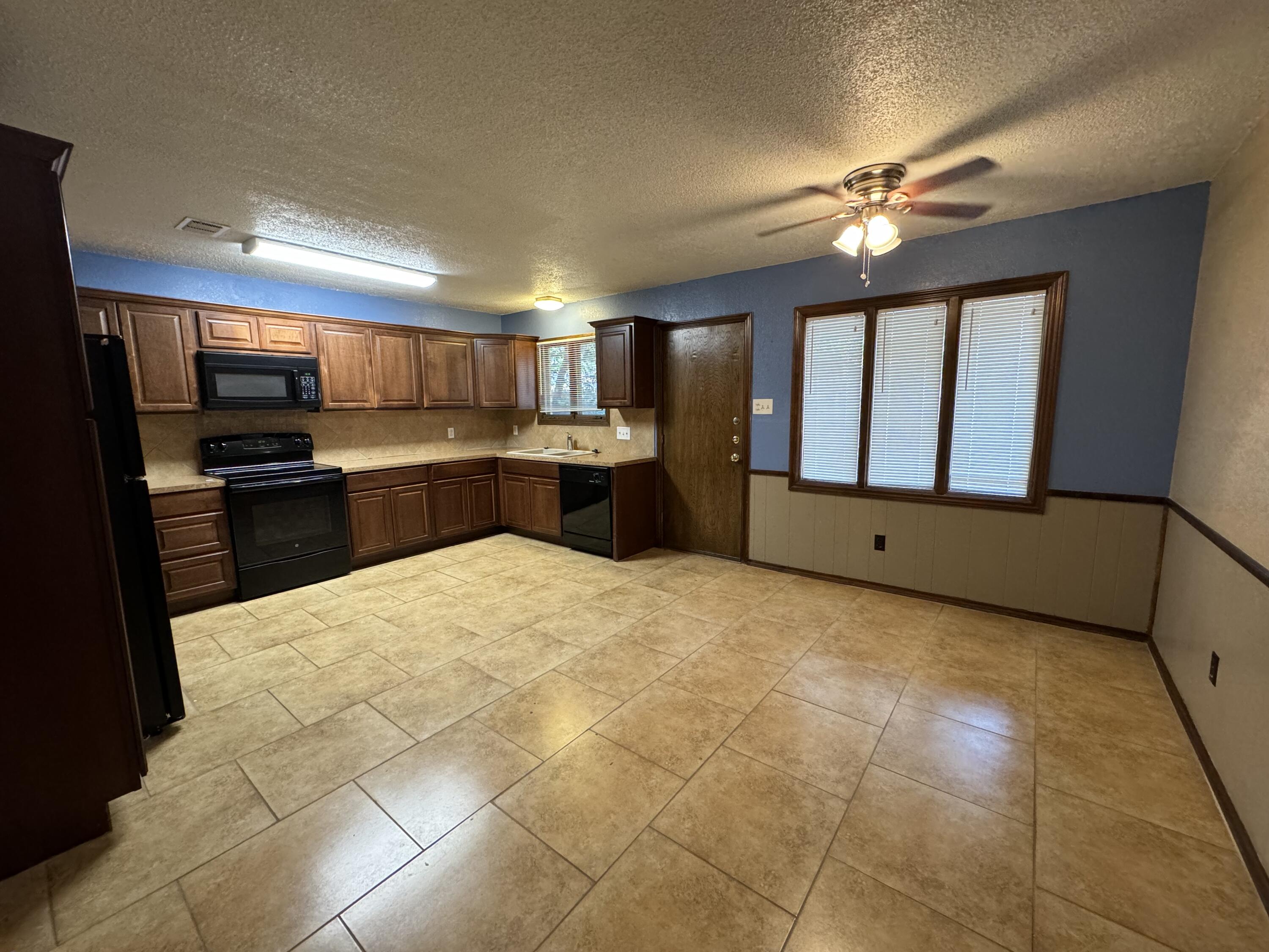 3103 75th Street, Unit B Lubbock, TX 79423 - Photo 14 of 22 a large kitchen with kitchen island granite countertop a refrigerator stove top oven and sink