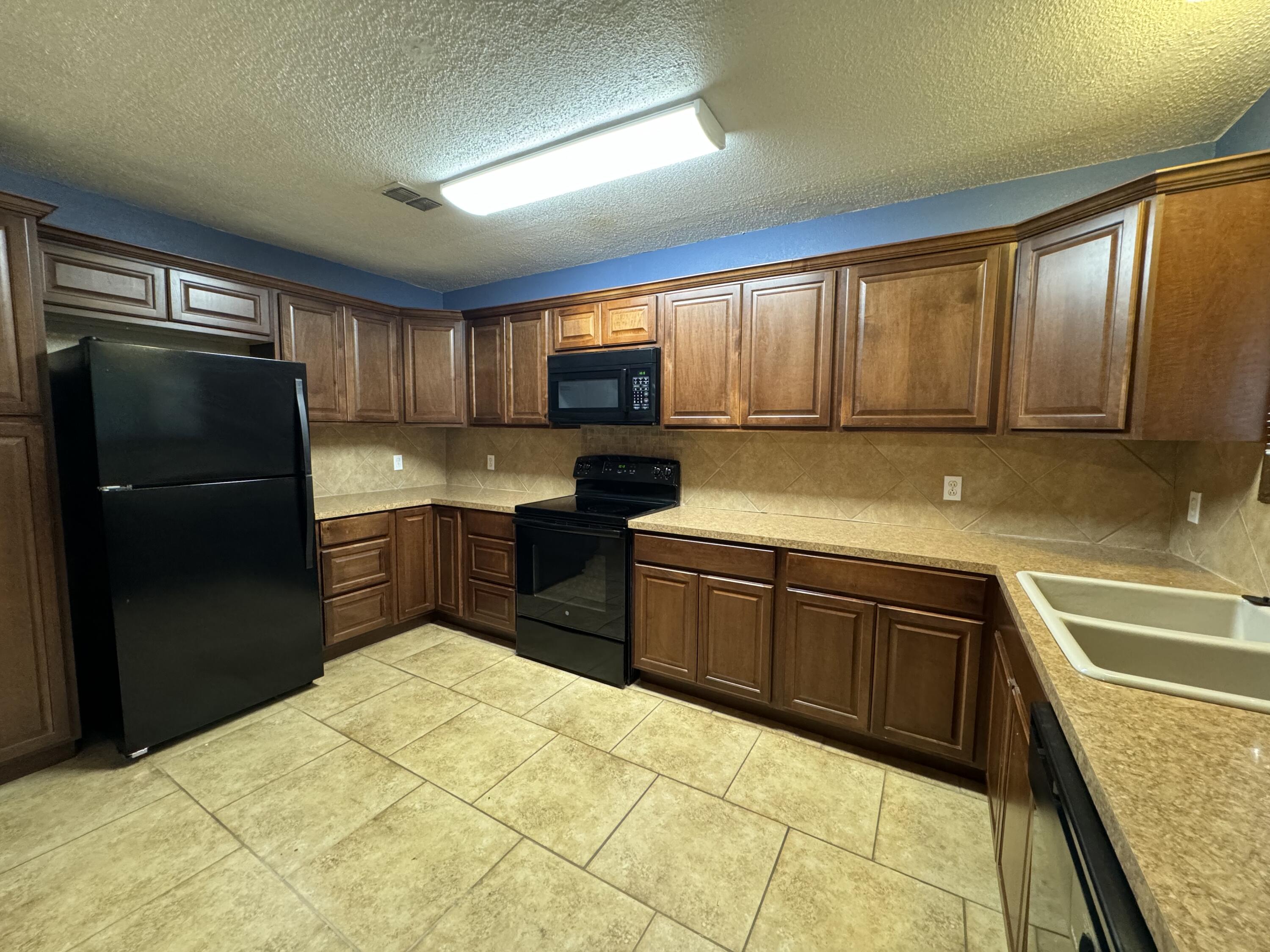 3103 75th Street, Unit B Lubbock, TX 79423 - Photo 15 of 22 a kitchen with granite countertop a refrigerator and cabinets