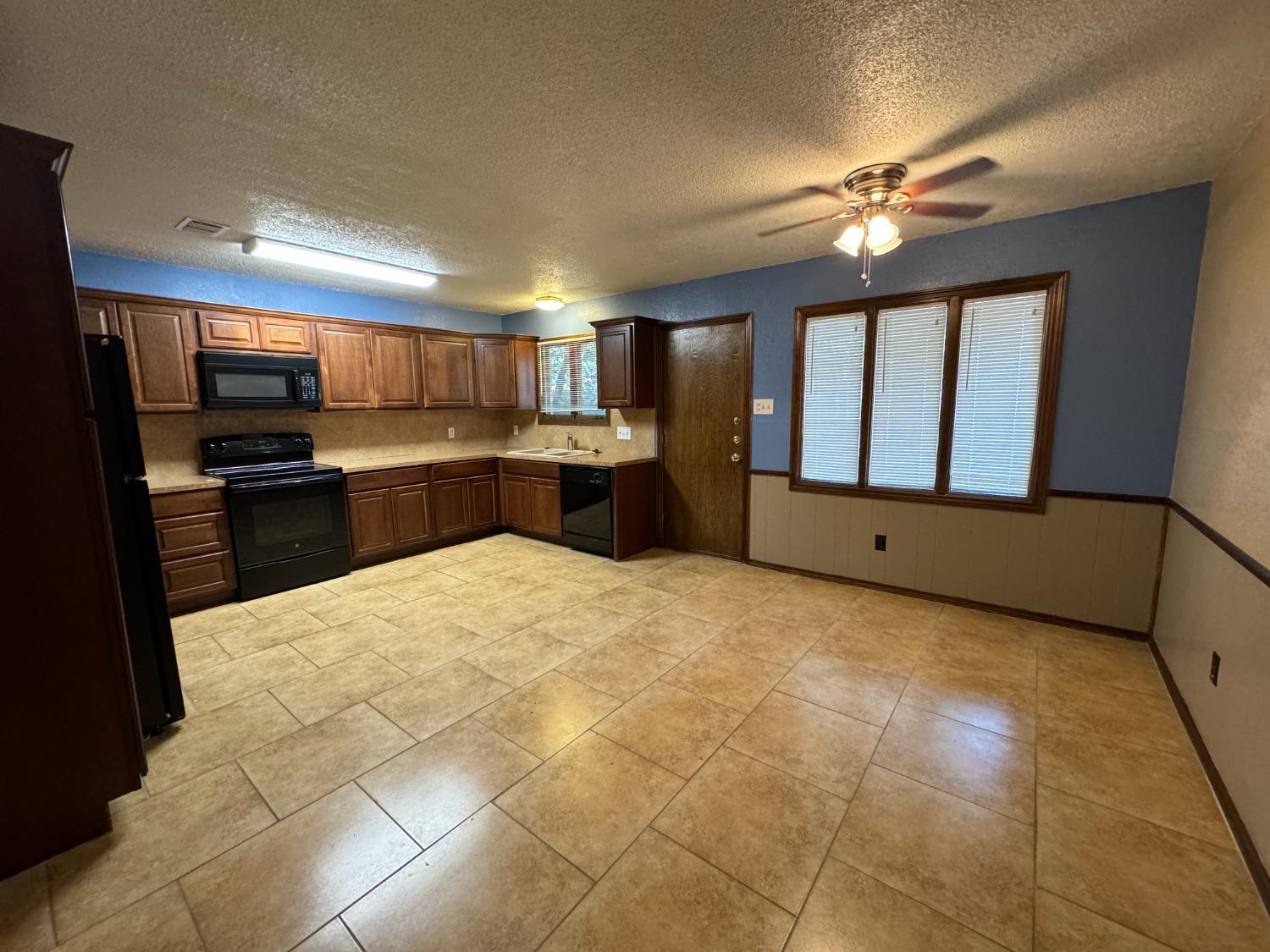 3103 75th Street, Unit B Lubbock, TX 79423 - Photo 3 of 22 a large kitchen with kitchen island granite countertop a refrigerator stove top oven and sink