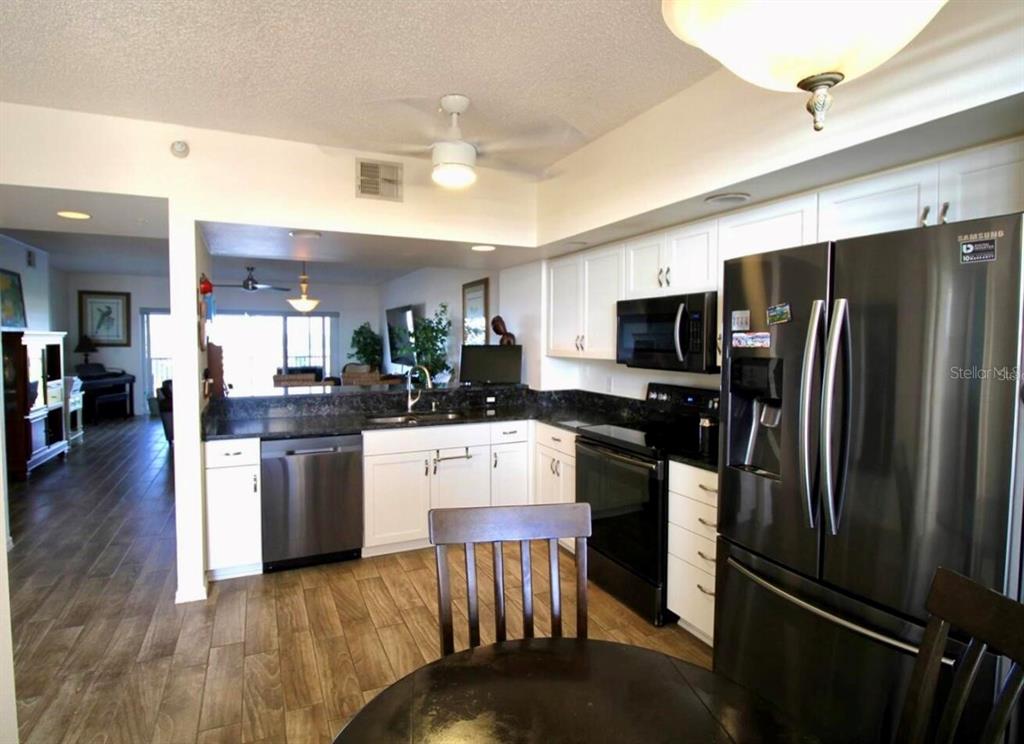 6425 Shoreline Drive, Unit 10503 St. Petersburg, FL 33708 - Photo 10 of 11 a kitchen with stainless steel appliances wooden floor and refrigerator