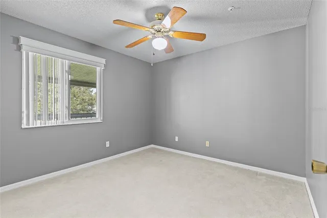 an empty room with a window and a fan