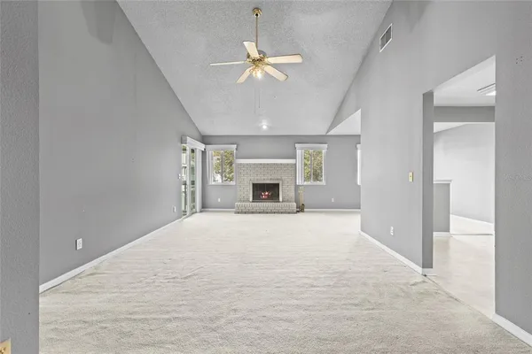 a view of an empty room with a fireplace and a chandelier fan
