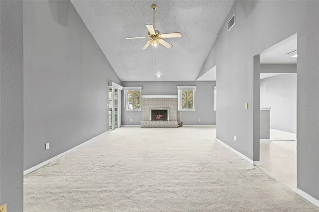 a view of an empty room with a fireplace and a chandelier fan