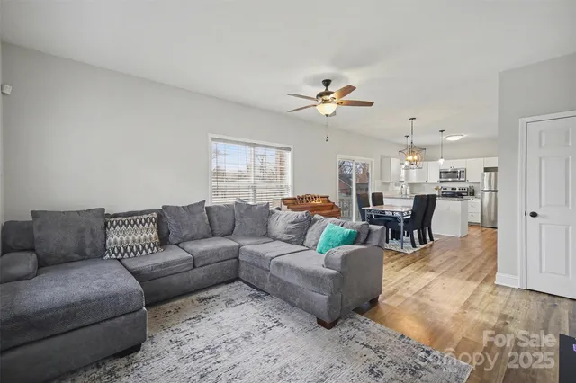 a living room with furniture kitchen view and a chandelier