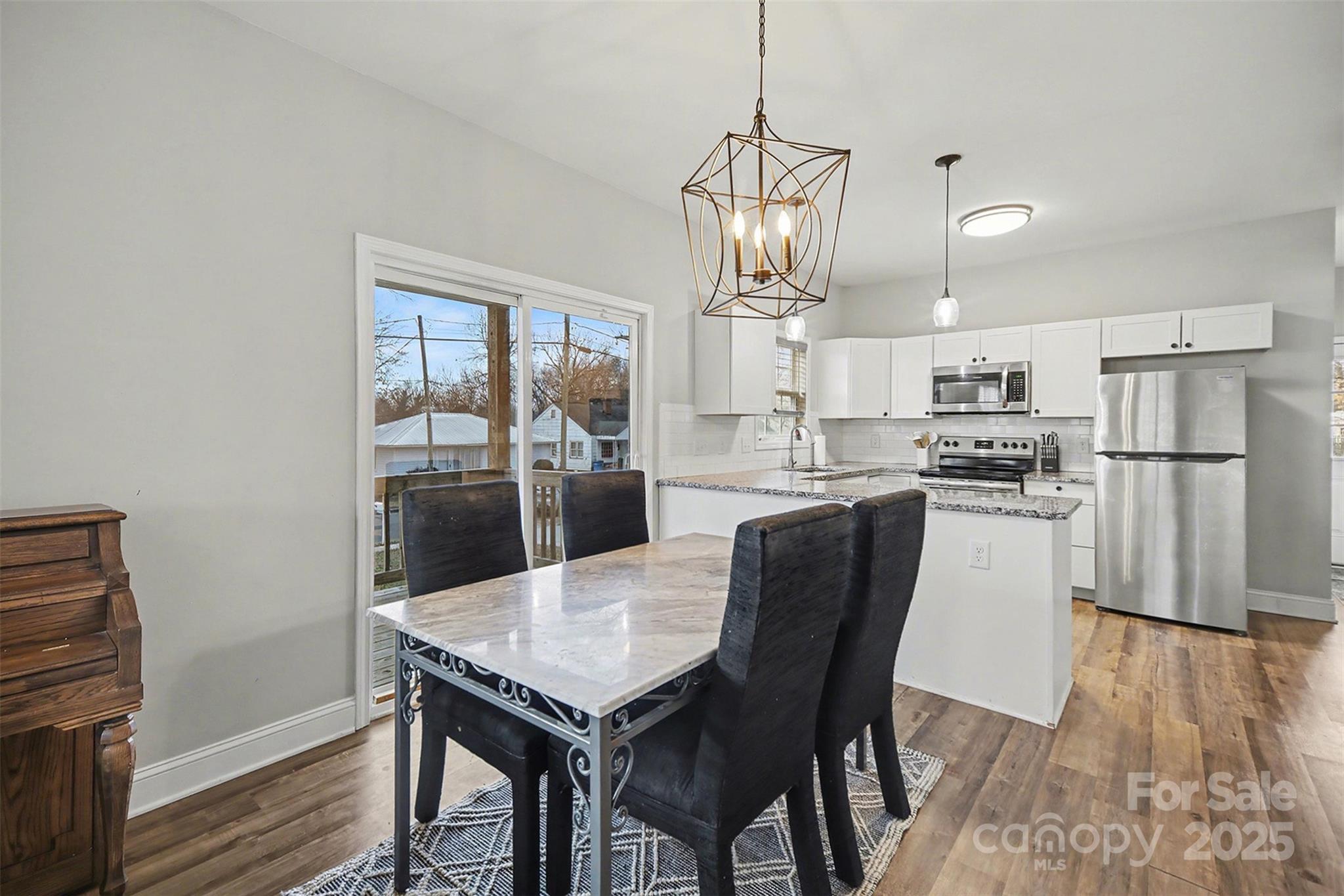 802 Lowder Street Albemarle, NC 28001 - Photo 7 of 22 a kitchen with stainless steel appliances granite countertop a dining table chairs refrigerator and wooden floor