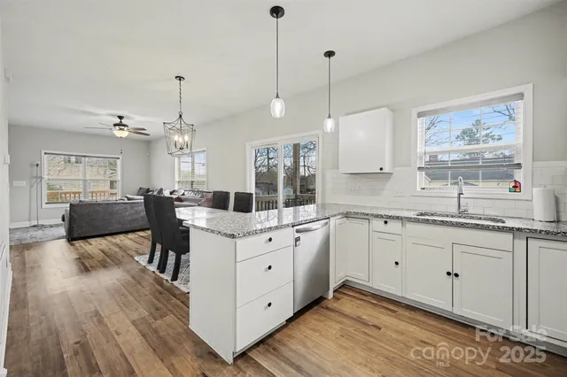 a large white kitchen with sink and wooden floor