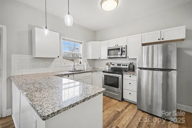 a kitchen with granite countertop a refrigerator a stove a sink dishwasher a oven with wooden cabinets and floor