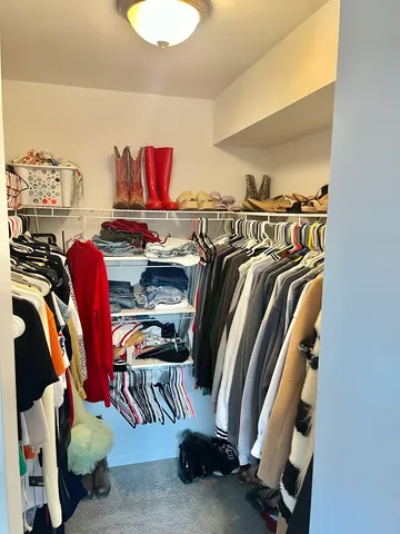 a view of walk in closet with clothes and shoes