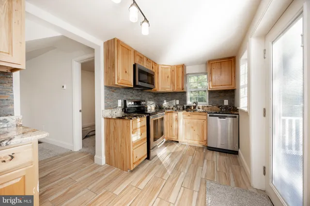 a kitchen with stainless steel appliances granite countertop a refrigerator a sink dishwasher a stove with wooden cabinets and floor