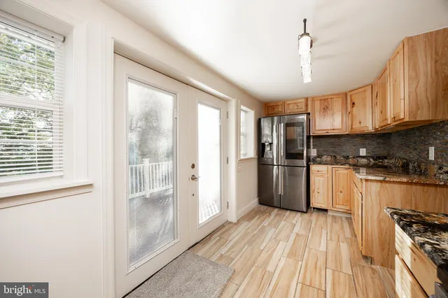 a kitchen with granite countertop a refrigerator a sink and white cabinets