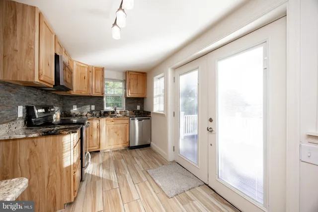 a kitchen with stainless steel appliances granite countertop a refrigerator a sink dishwasher a stove and white countertops with wooden floor