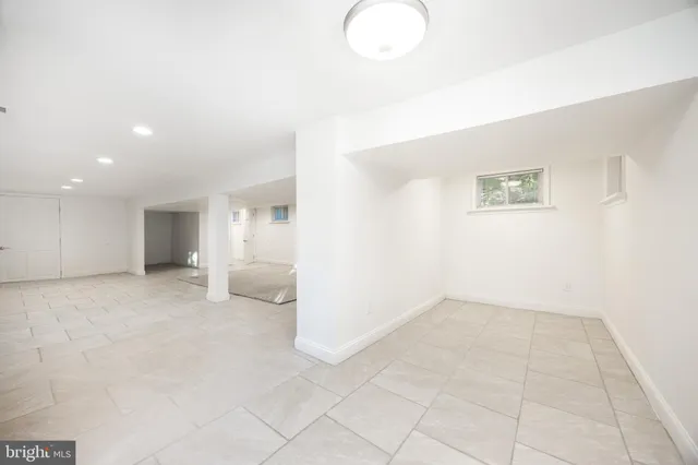 an empty room with kitchen view with wooden floor