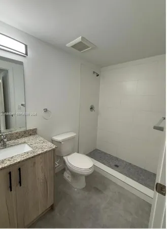 a bathroom with a granite countertop sink a toilet a mirror and shower