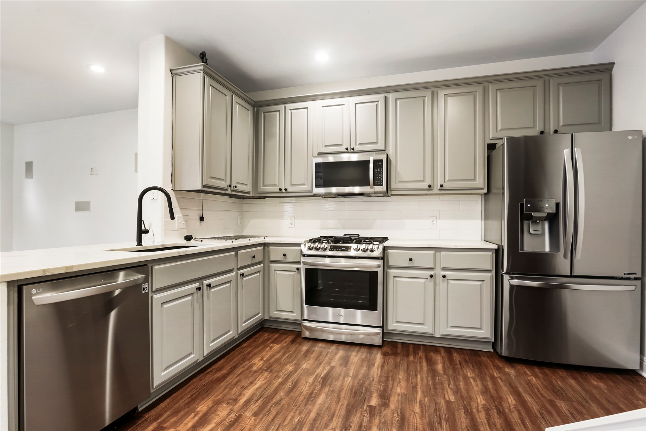 3406 Menchaca Road, Unit 19 Austin, TX 78704 - Photo 9 of 25 Gleaming wood floors anchor this kitchen completed with classic shaker cabinets and modern appliances.