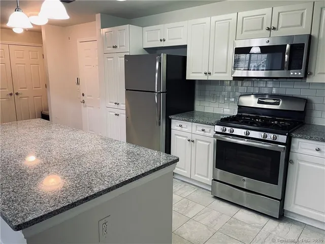 a kitchen with stainless steel appliances granite countertop a stove a refrigerator and a sink