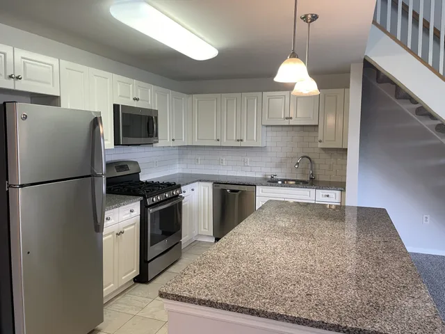 a kitchen with stainless steel appliances granite countertop a refrigerator a stove a sink and a center island