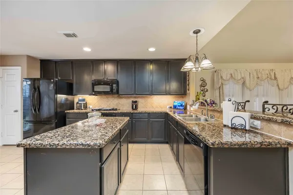 a kitchen with kitchen island granite countertop a sink counter top space appliances and cabinets