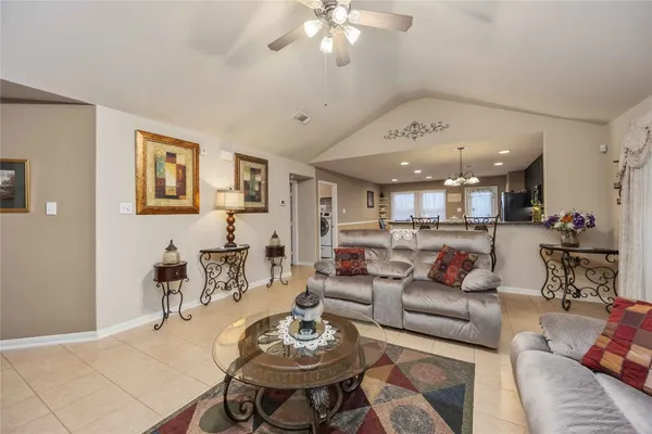 a living room with furniture kitchen view and a chandelier
