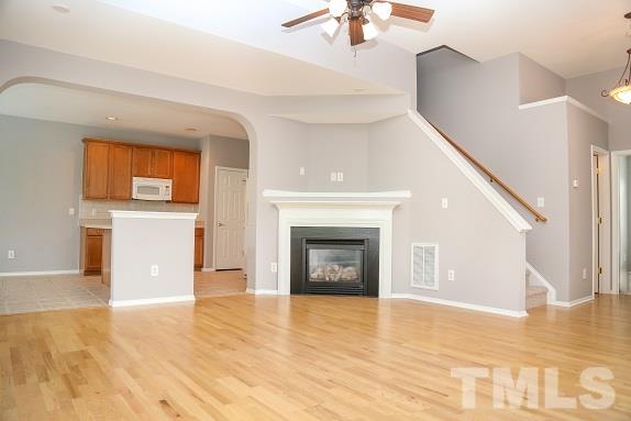 8312 Chimneycap Drive Raleigh, NC 27613 - Photo 5 of 25 a view of a livingroom with a fireplace a ceiling fan and wooden floor