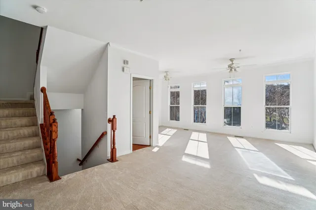 a view of an empty room with wooden floor and windows