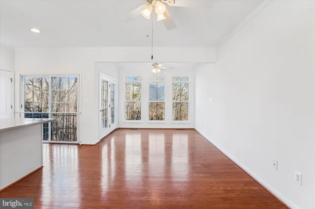 a view of an empty room with wooden floor and a large window