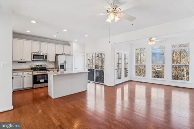 a kitchen with stainless steel appliances kitchen island wooden floors and white cabinets