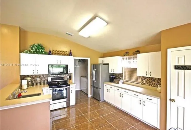 a large kitchen with stainless steel appliances a stove a sink and a refrigerator
