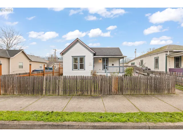a view of a white house with a small yard and a large tree