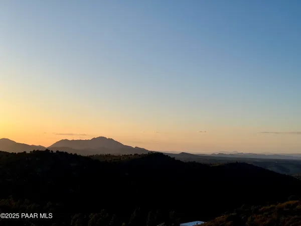 a view of mountain with sunset in background