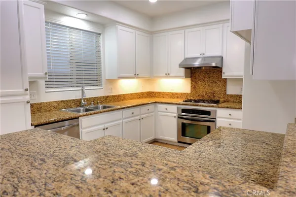 a kitchen with stainless steel appliances granite countertop a stove a sink and a refrigerator