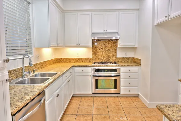 a kitchen with granite countertop a sink stainless steel appliances and cabinets