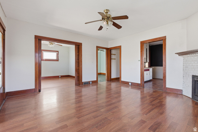 869 West Center Street Provo, UT 84601 - Photo 11 of 32 Unfurnished living room with dark wood-style floors, ceiling fan, and a brick fireplace