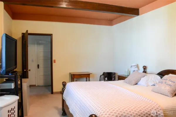 a bedroom with a bed and a flat tv screen on dresser