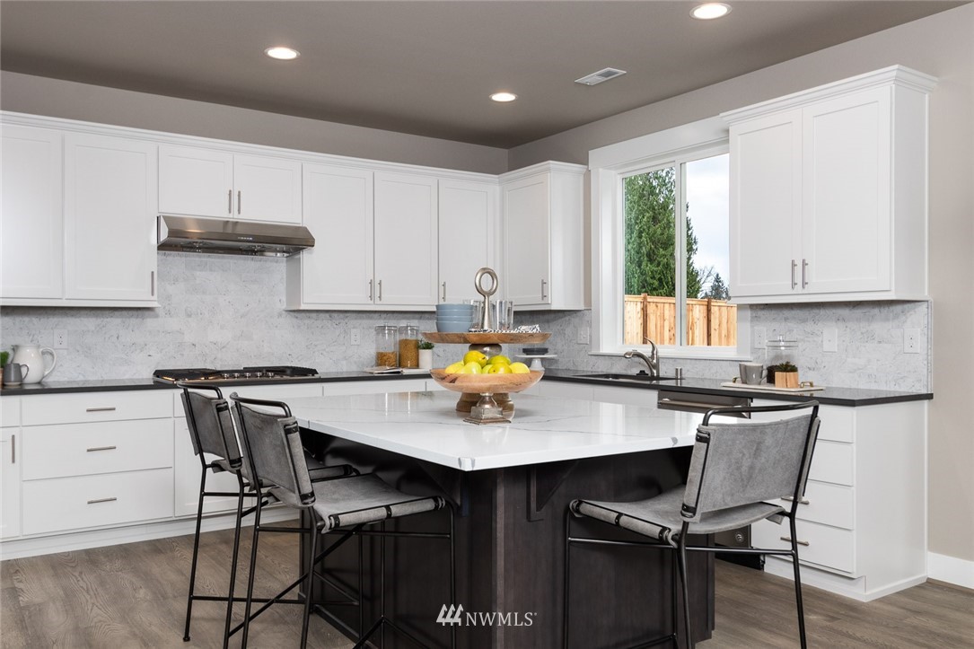 6515 Southeast 2nd Place Renton, WA 98059 - Photo 7 of 29 a kitchen with stainless steel appliances granite countertop a table chairs sink and white cabinets