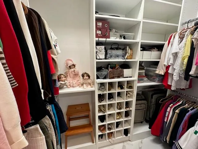 a view of walk in closet with clothes and shoes