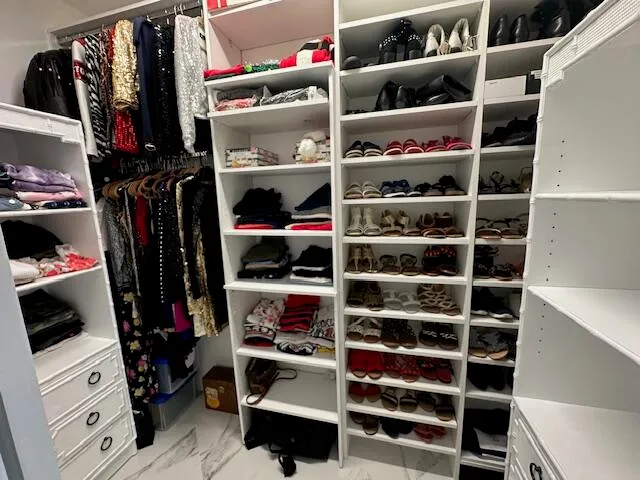 a view of walk in closet with clothes and shoes