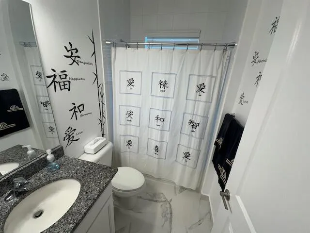 a bathroom with a granite countertop sink toilet and shower