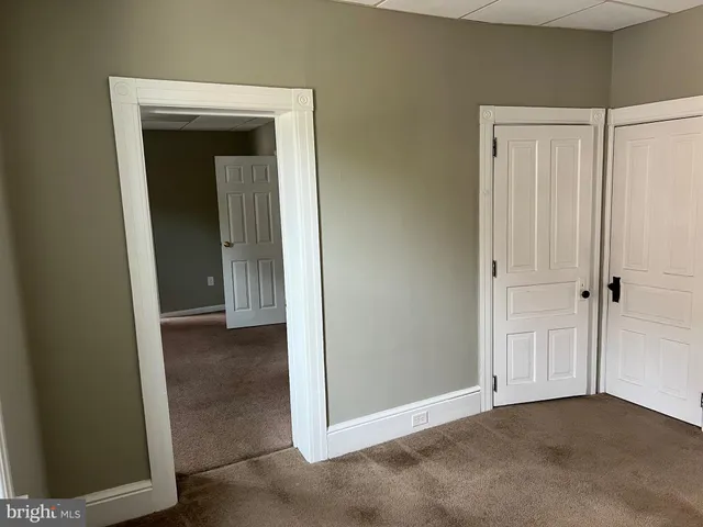 a view of an empty room with closet and a bathroom