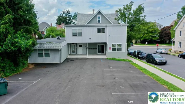 a view of a house with a yard and large parking space