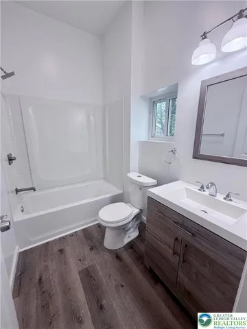 a bathroom with a bathtub shower sink vanity mirror and toilet
