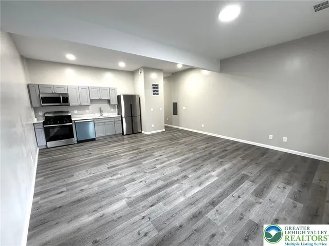a view of kitchen view wooden floor and stainless steel appliances