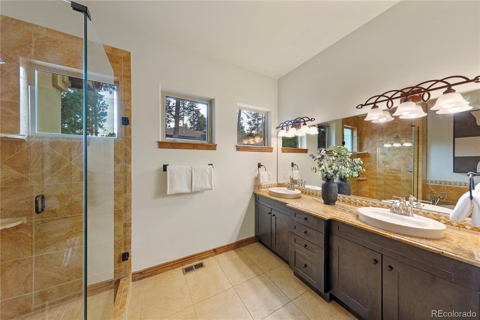 590 Cumberland Road Larkspur, CO 80118 - Photo 16 of 47 a spacious bathroom with a double vanity sink a mirror and a shower