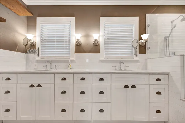 a bathroom with double vanity and a mirror