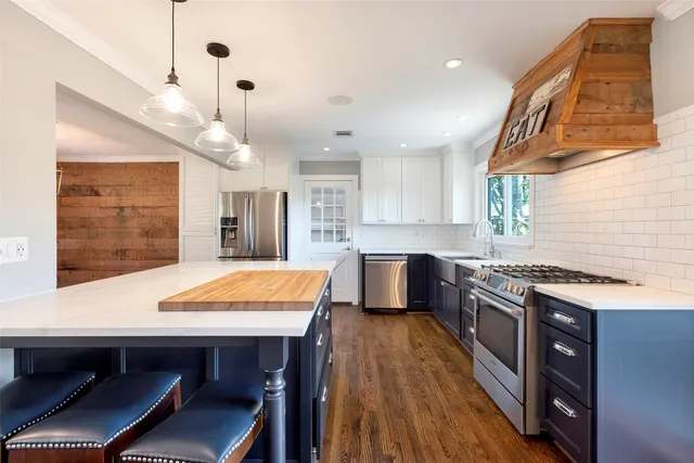 a kitchen with stainless steel appliances granite countertop table chairs sink and wooden floor