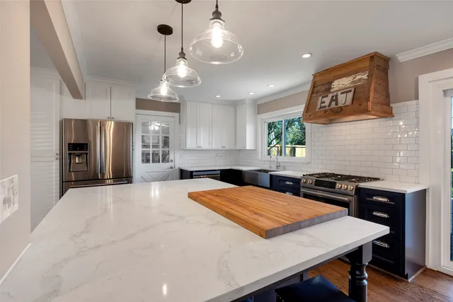 a kitchen with stainless steel appliances kitchen island granite countertop a table chairs in it and wooden floors