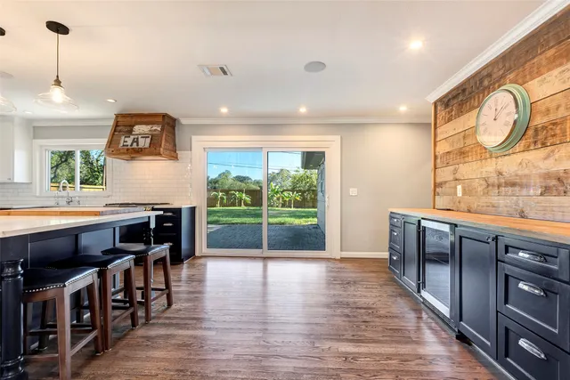 a open kitchen with stainless steel appliances granite countertop a stove a refrigerator a dining table and chairs with wooden floor