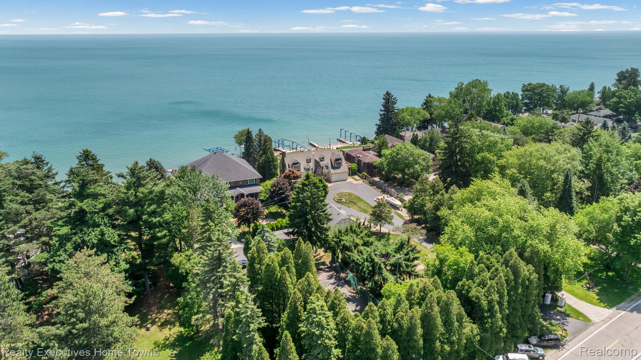 8308 Lakeshore Road Fort Gratiot, MI 48059 - Photo 24 of 79 Waterfront property featuring extensive mature tree landscaping, a private drive, and multiple structures set against a vast body of water